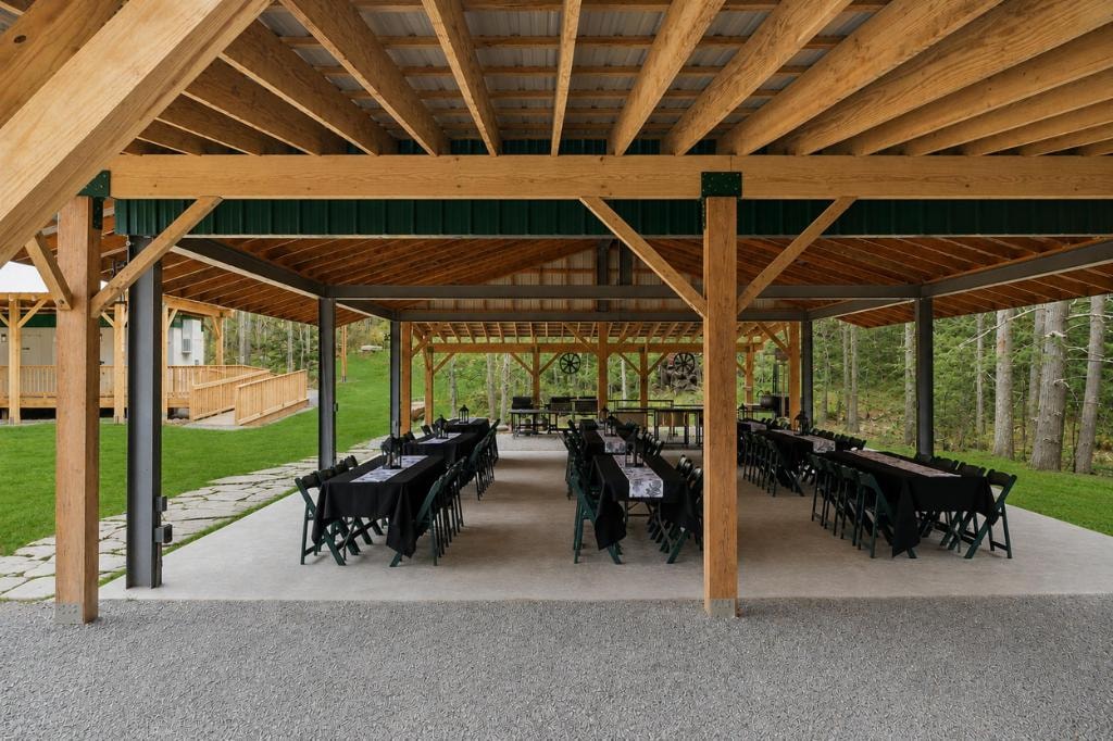 Ramble On Inn open-air pavilion with timber frame ceiling, long tables with black linens and green chairs