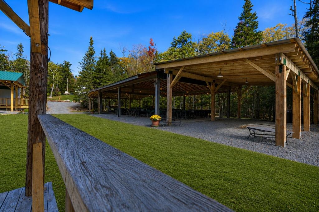 Ramble On Inn open-air pavilion and green lawn on a sunny day with forest backdrop